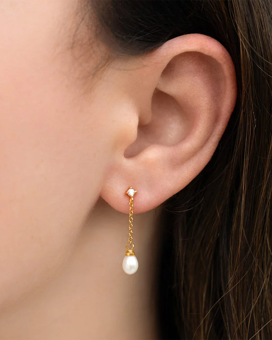 model wearing gold dangle earrings with crystal stud and pearl drop