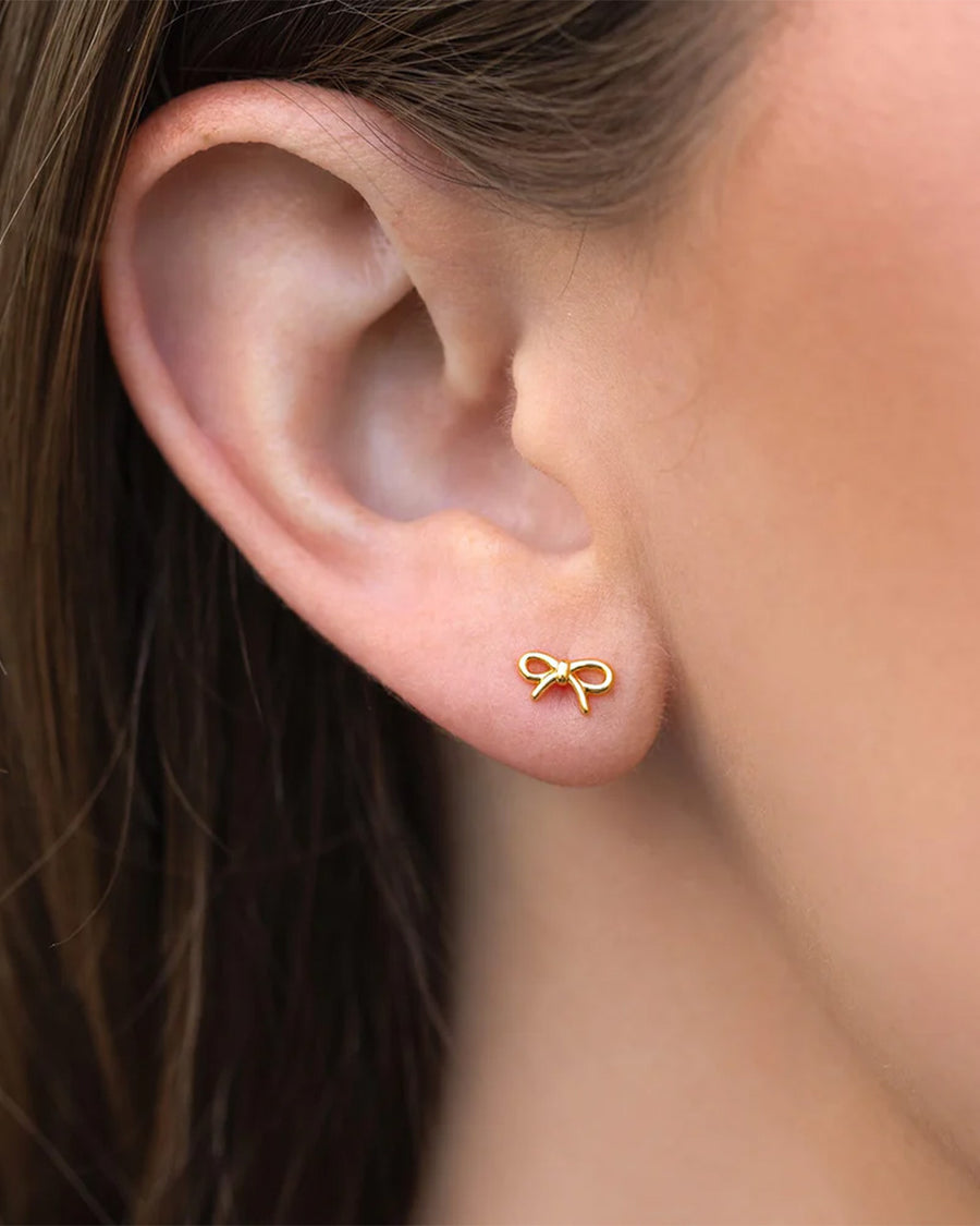 model wearing gold tiny bow stud earrings