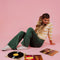 model wearing forest green corduroy bell bottoms with orange and yellow cardigan surrounded by records