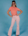 model wearing powder pink corduroy bell bottoms with melon colored polo