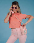 top view of model wearing powder pink corduroy bell bottoms with melon colored polo