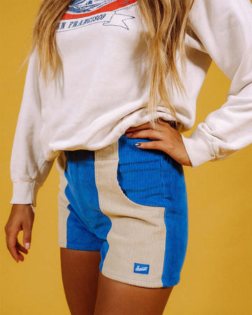 model wearing two-tone corduroy shorts in sand and bright blue