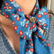model wearing brass floral scarf slide + ring in a tied scarf