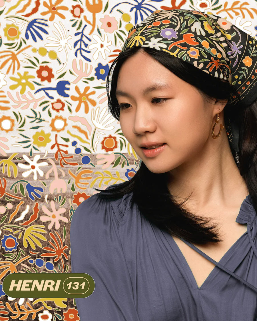 model wearing black square cotton bandana with colorful abstract floral print in their hair