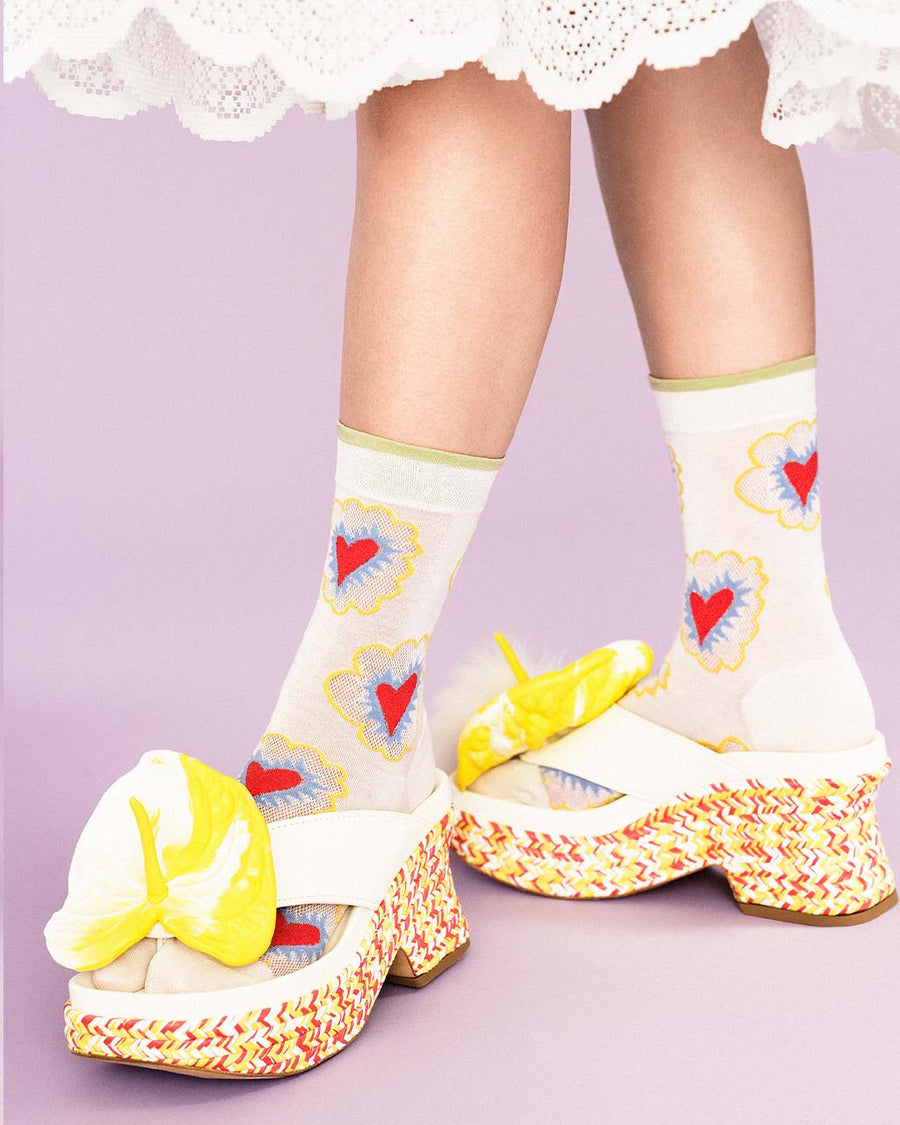 up close of model wearing white crew socks with abstract heart pattern and green trim