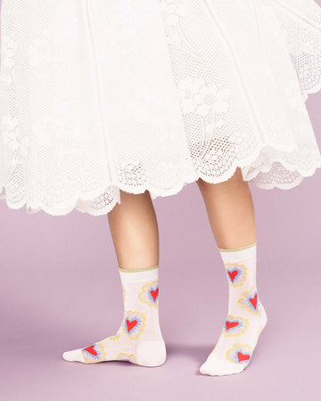 model wearing white crew socks with abstract heart pattern and green trim