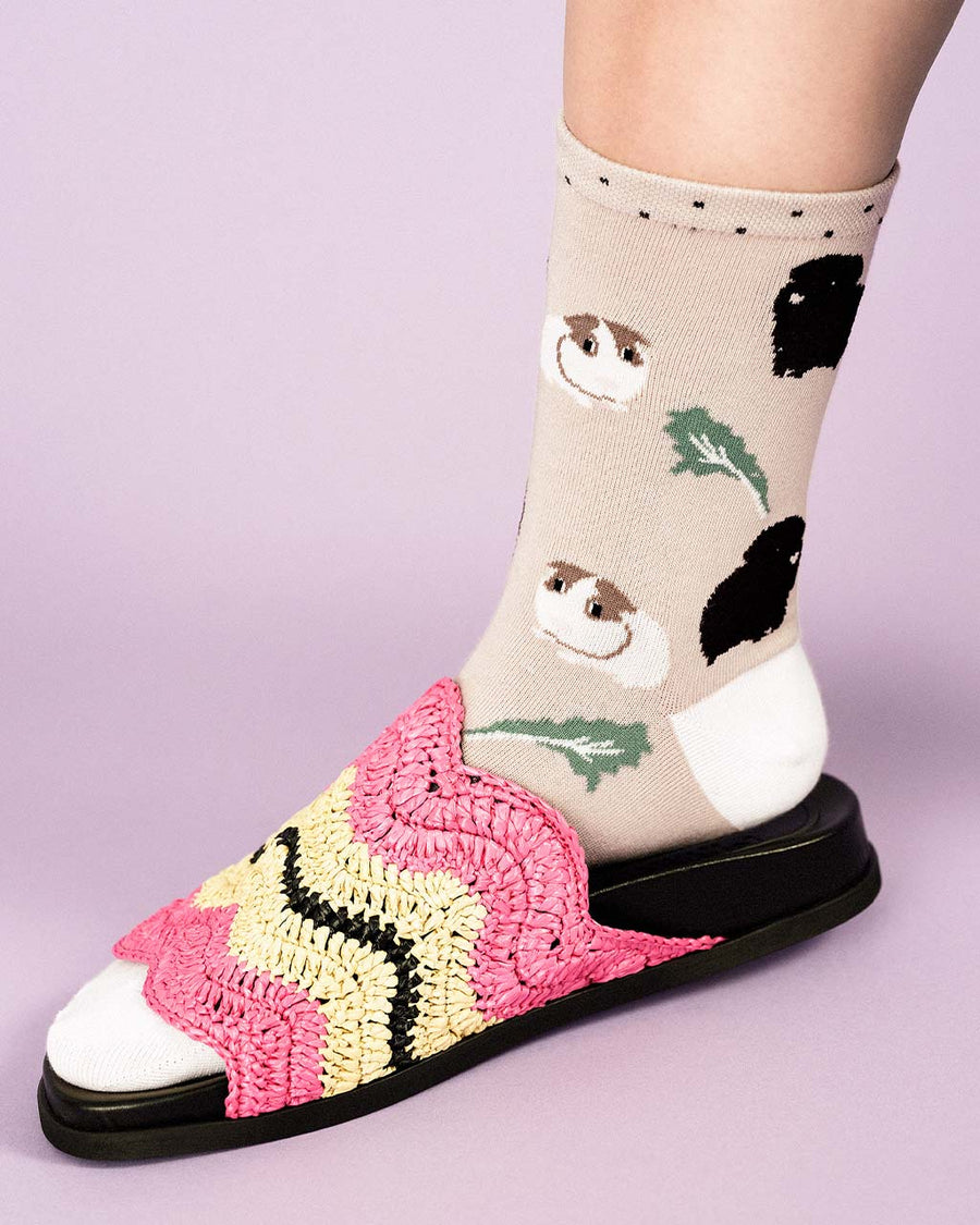 up close of model wearing beige crew socks with guinea pig and leaf print