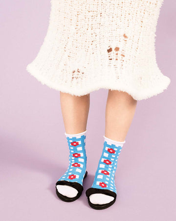 model wearing blue and white plaid crew socks with red floral print