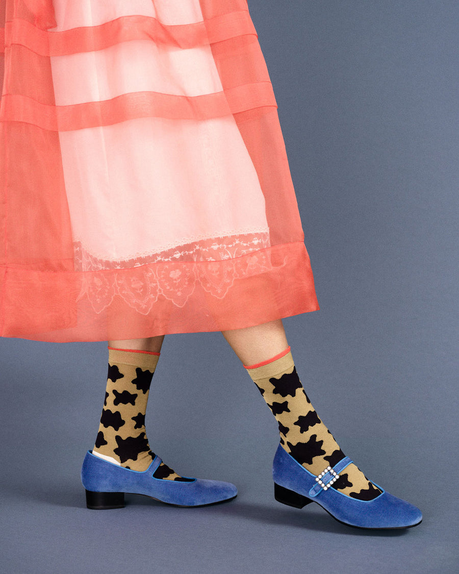 model wearing camel socks with red trim and black blobs print