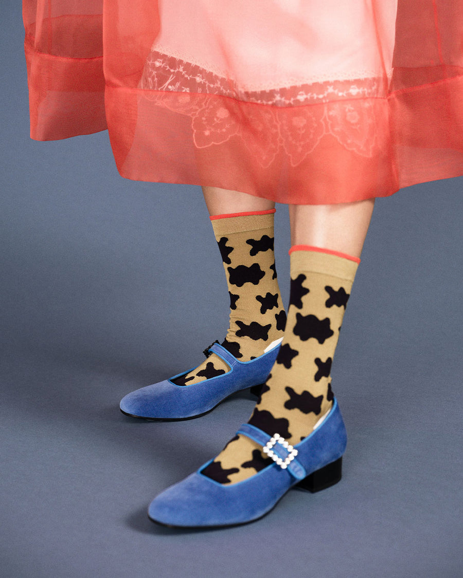 up close of model wearing camel socks with red trim and black blobs print