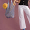 model holding fog paper crochet bag with bread and flower in it