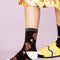 up close of model wearing black socks with brown dog and daffodil print