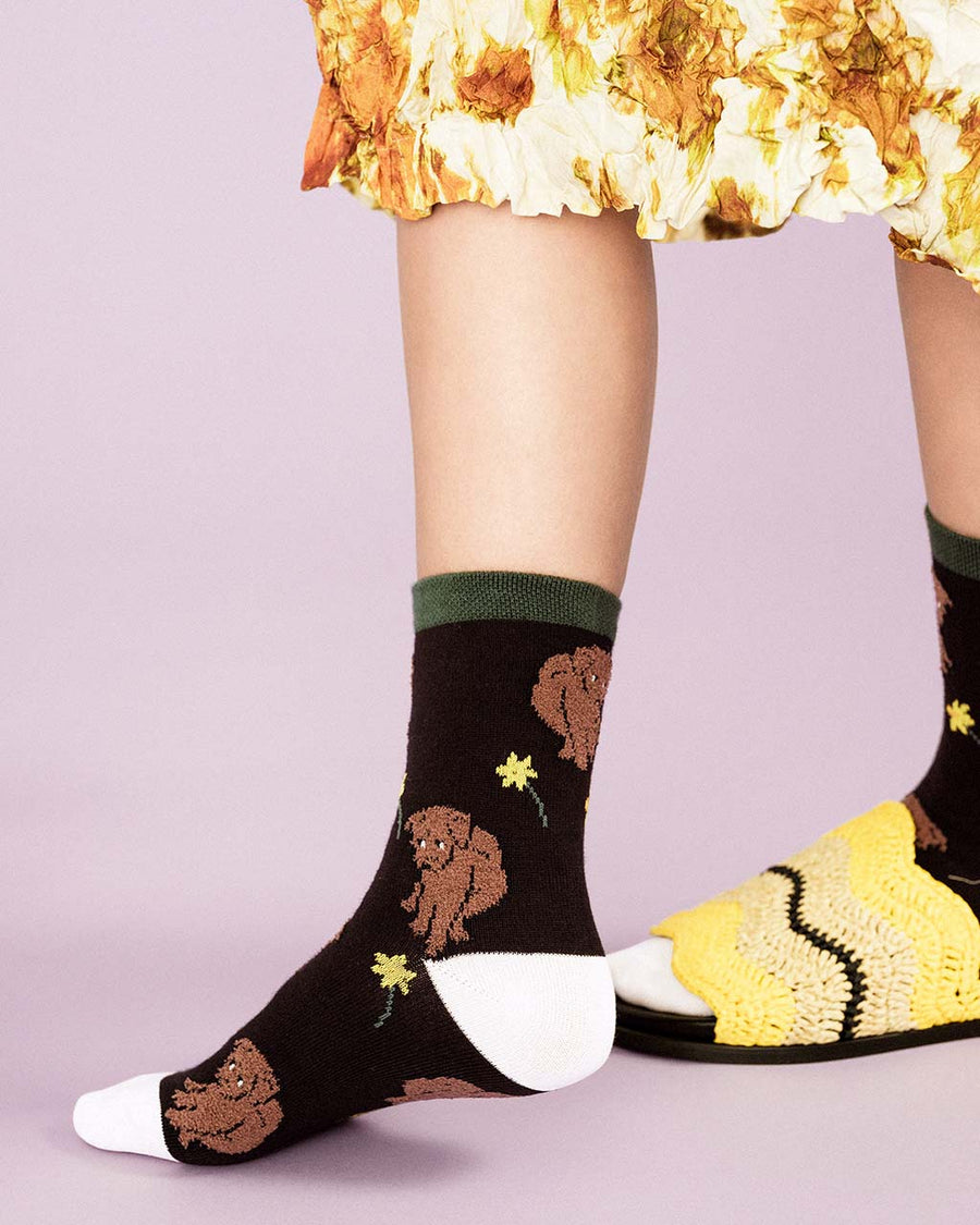 up close of model wearing black socks with brown dog and daffodil print