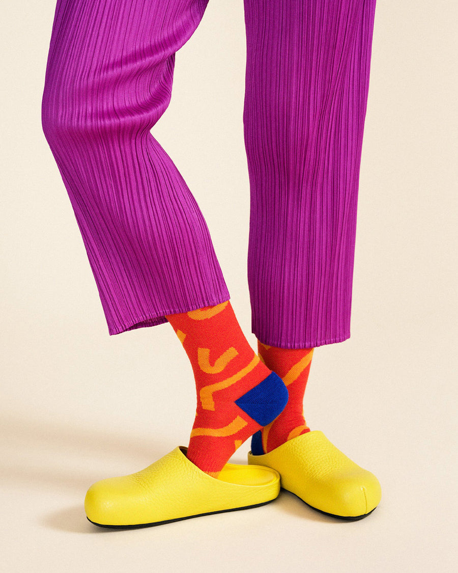 model wearing red socks with orange squiggles and royal blue heel and toe detail