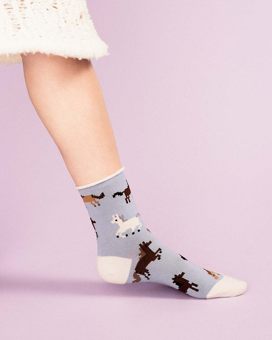 up close of model wearing slate blue crew socks with pixelated horse print