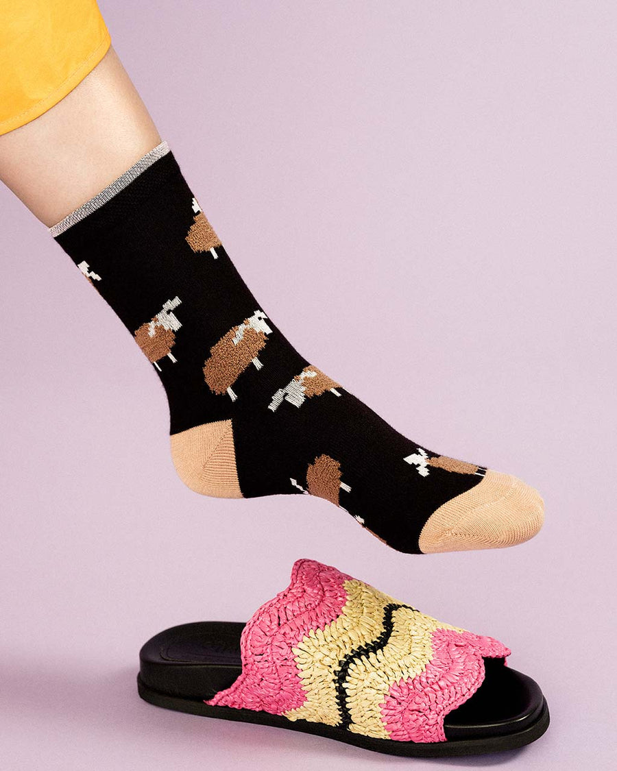 up close of model wearing black socks with brown sheep print