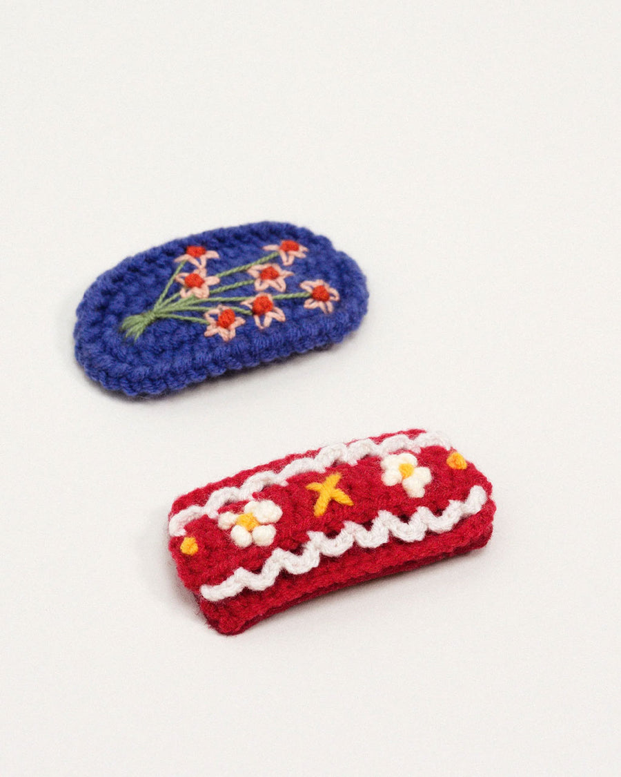up close of set of two crochet hair clips: blue floral and red floral