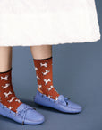 up close of model wearing red high socks with all over cat and dog print