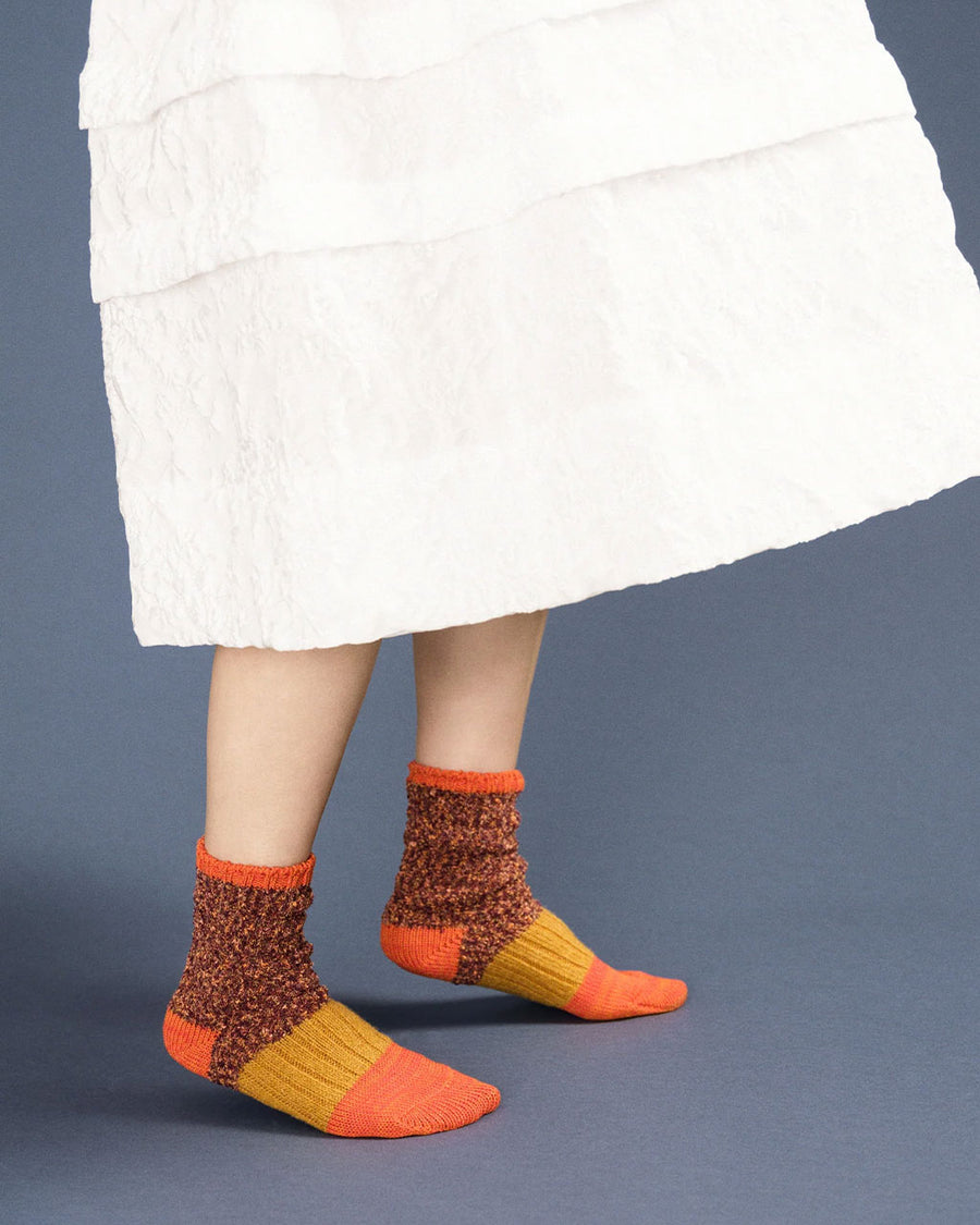 side view of model wearing chunky socks with orange, yellow and brown color blocking