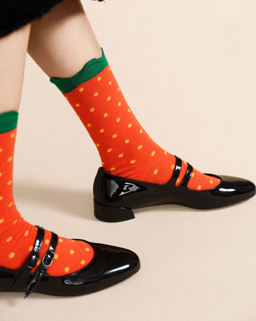 model wearing red strawberry socks with yellow dots and green scalloped top hem