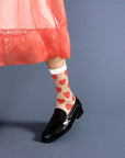 up close of model wearing sheer crew socks with red heart print