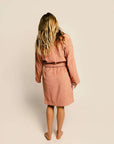 backview of model wearing terra cotta robe with embossed smiley design and front patch pockets