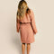 backview of model wearing terra cotta robe with embossed smiley design and front patch pockets
