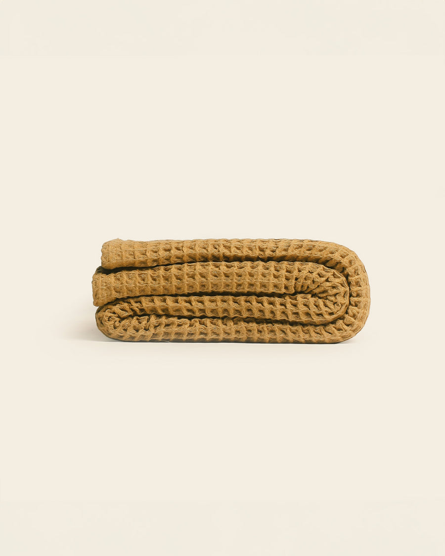 side view of honey mustard cotton waffle throw blanket