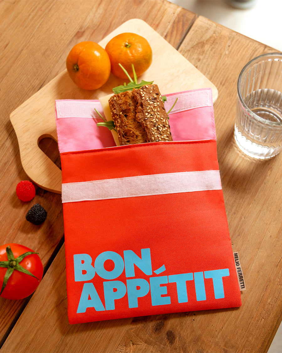 pink and coral snack bag with light blue 'bon appetit' across the front on a table