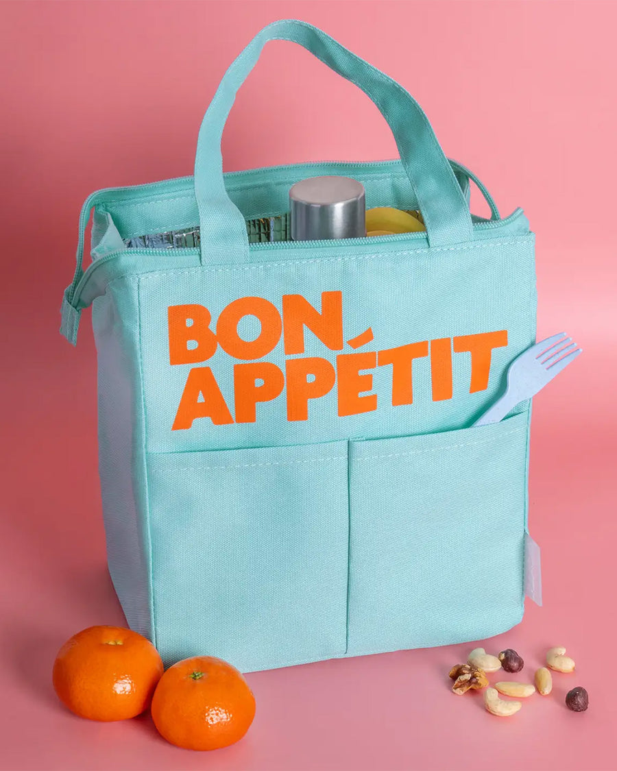 light blue lunch bag with orange 'bon appetit' across the front on a pink background