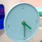 blue round clock with green hands on a shelf