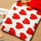white small beaded clutch with red tassel and red beaded heart design surrounded by change, keys and earbuds