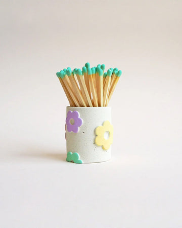 white speckled matchstick holder with pastel colored daisies
