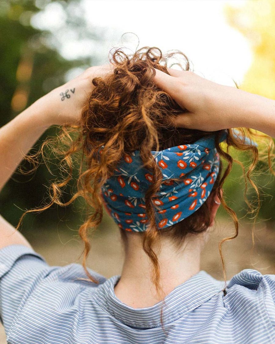 model wearing blue bandana with all over red floral print as a headband