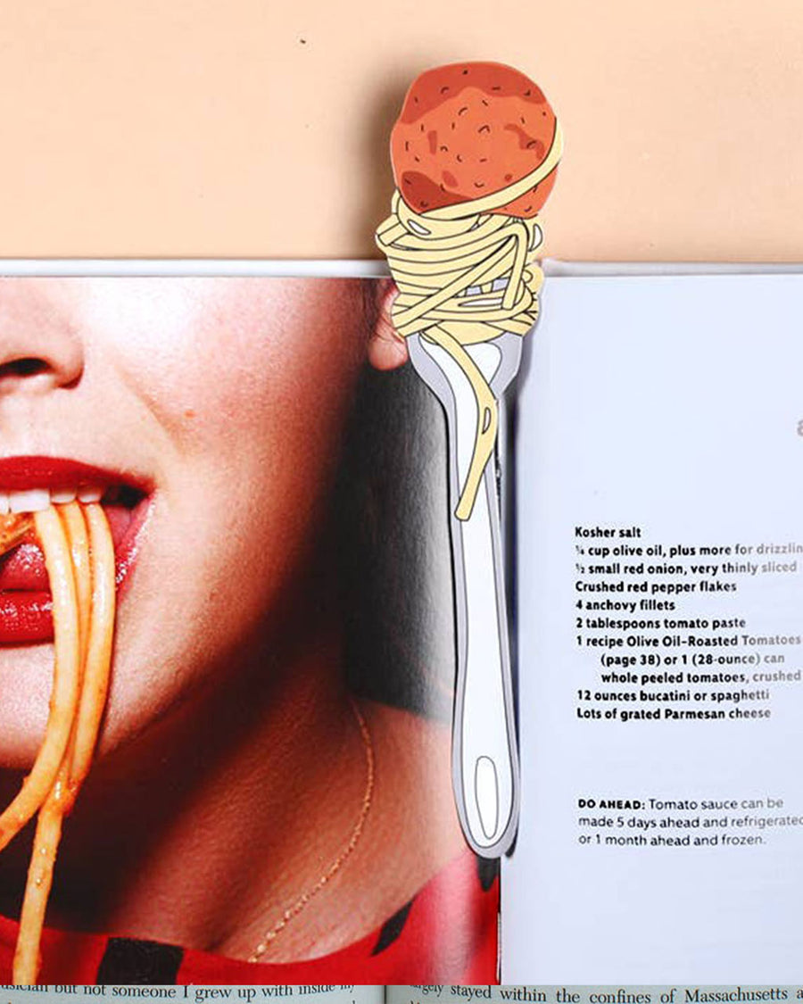 meatball and spaghetti twirled on fork bookmark in open book
