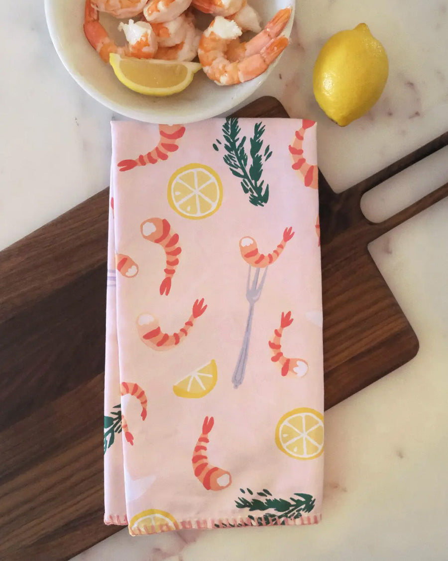 folded light pink cotton tea towel with shrimp cocktail and lemon print