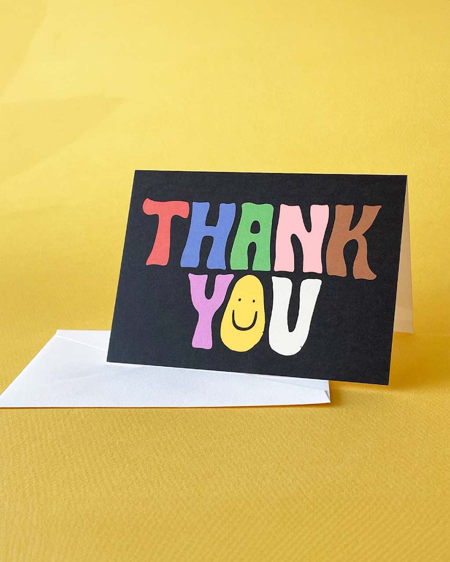 thank you card set of 12 with black ground and wavy 'groovy' colorful 'thank you' with a smiley face