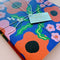 packaged set of two notebooks: blue wavy daisy and orange abstract floral