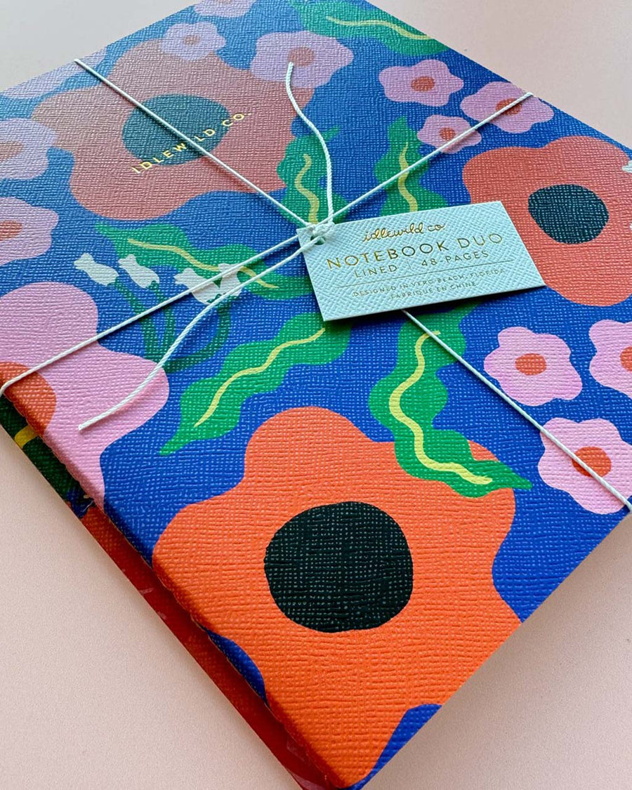 packaged set of two notebooks: blue wavy daisy and orange abstract floral
