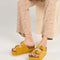 model wearing marigold platform shoes with two buckle straps and grommet details on the sides