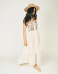 model wearing white maxi dress with pink flower bodice and vertical line detail throughout the dress