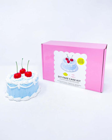 blue fake cake kit with red cherries on top and box next to it