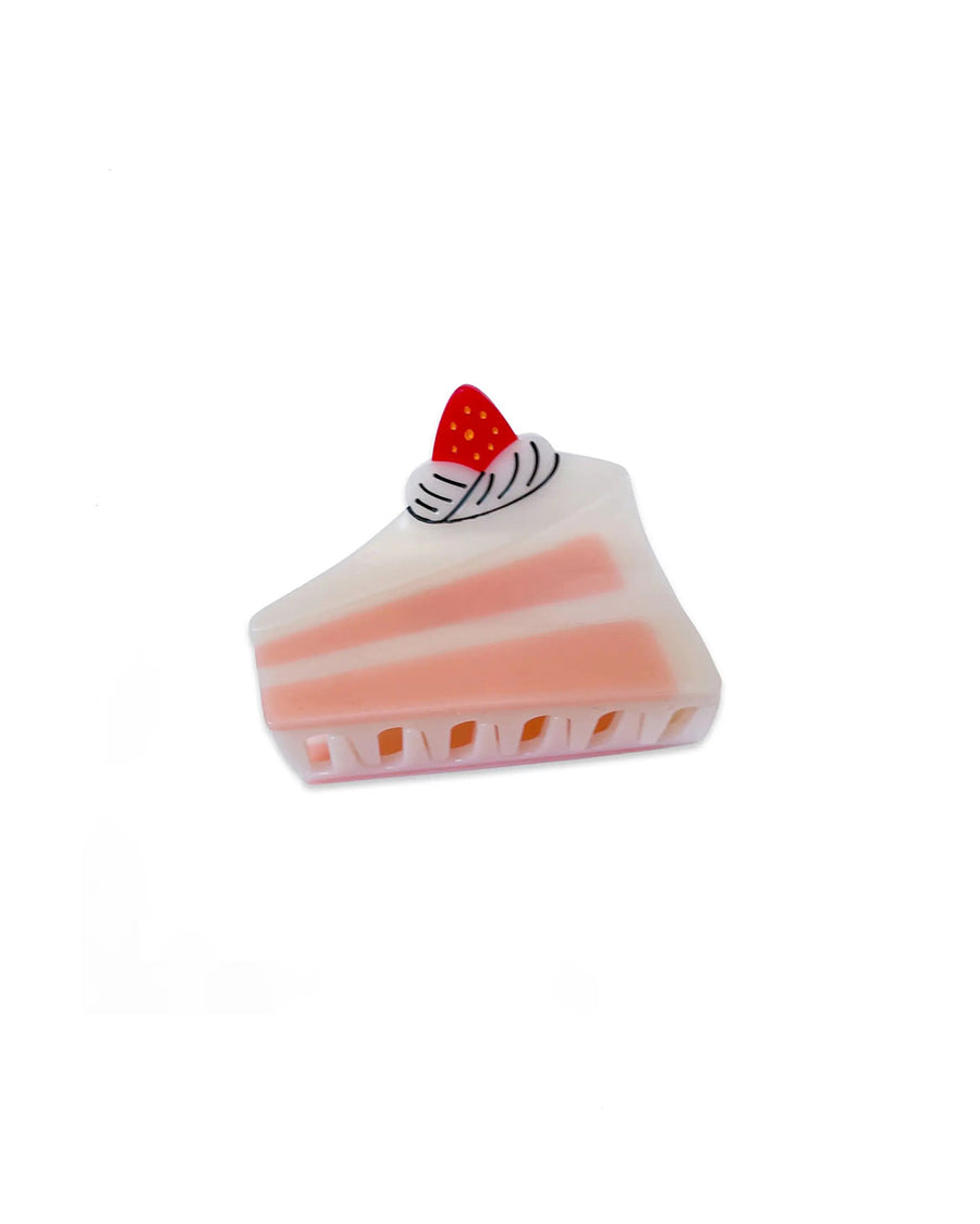 side view of cake hair clip with pink and white details and a strawberry on top