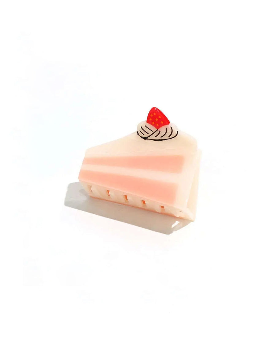 bottom view of cake hair clip with pink and white details and a strawberry on top