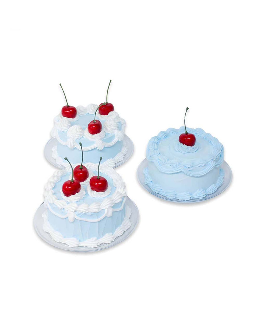different variations of blue fake cake kit with red cherries on top