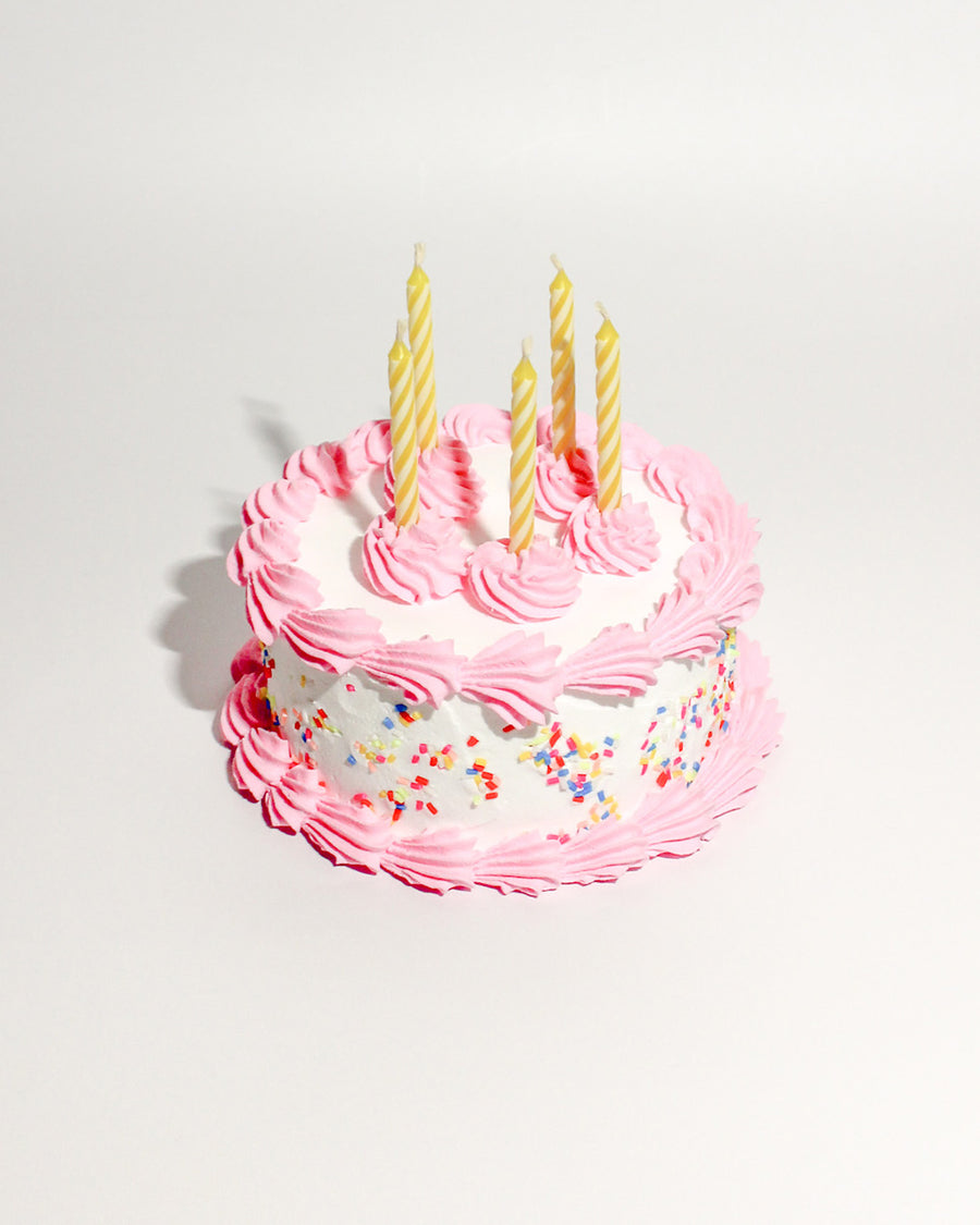 white fake cake kit with pink 'frosting', colorful faux sprinkles and yellow candles