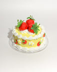 yellow fake cake kit with white 'frosting' and faux strawberries on plate
