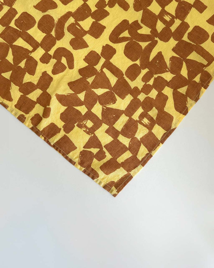 up close of set of two yellow cloth napkins with brown check pattern