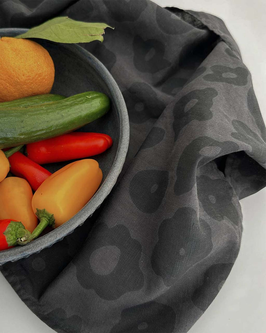 faded black tea towel with black floral print with a bowl of peppers on it