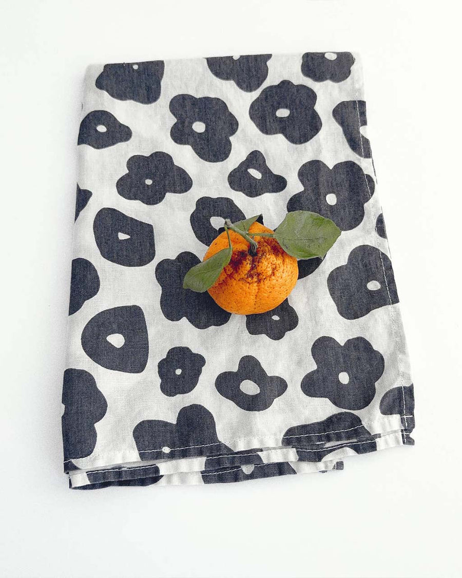 white tea towel with black floral print with orange on it